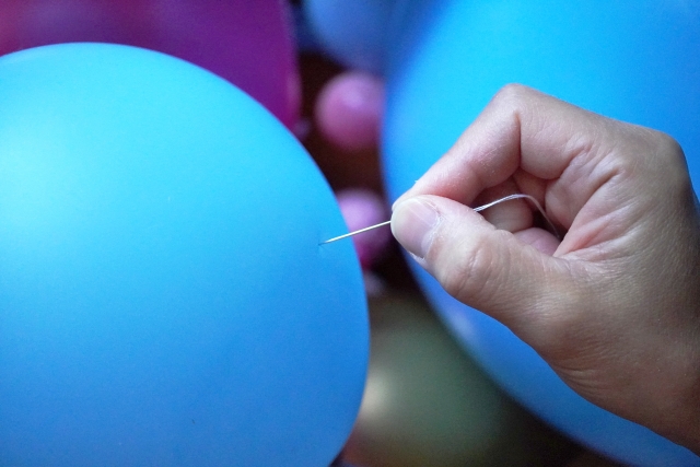 パンパンに膨らんだ風船を割ろうとしているところ