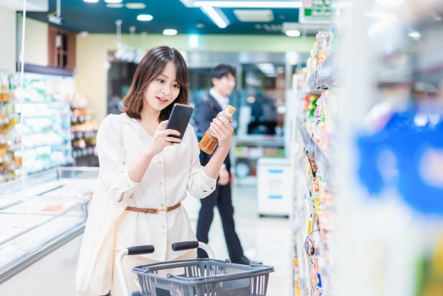 スーパーの商品をスマホで調べる女性